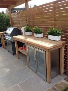 an outdoor kitchen with potted plants on the counter and grill in the back yard