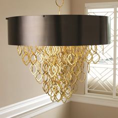 a gold chandelier hanging from the ceiling in a room with white walls and windows