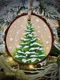 a christmas tree ornament hanging from a tree branch with snow on the branches