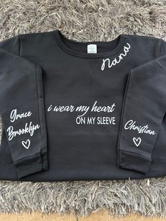 Custom made to order I wear my heart on my sleeve sweatshirt with kids names on sleeves.  Options for neckline:  Mama, nana, yaya, etc (message for more) I wear my heart on my sleeve center can be customized to other sayings:  Mama EST (year)  Boy Mama Girl Mama Nana  Grandma  And many more options (message for more details) Colors available: Black, grey, white, navy blue, light pink  Sizes available: S M L XL XXL   50/50 poly/ cotton blend- pre shrunk sweatshirt.  For more customization options please message :)  Vinyl colors: white, black, glitter options available also. Personalized Long Sleeve Cotton Sweatshirt, Custom Name Long Sleeve Cotton Sweatshirt, Nana Sweatshirt, Heart On My Sleeve, Nana Grandma, Boy Mama, Kids Names, Mama Sweatshirt, Heart On