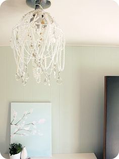 a chandelier hanging from the ceiling over a desk in a room with green walls