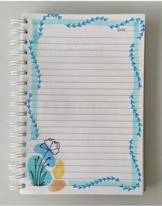 an open notebook with blue and yellow flowers on the page, next to a pen