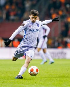 a man kicking a soccer ball on top of a field