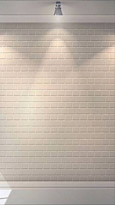 an empty room with a white brick wall and two spotlights on the ceiling above it