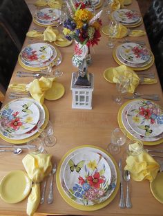 the table is set with yellow and white plates, silverware, and napkins