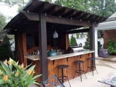 an outdoor kitchen with bar stools and table