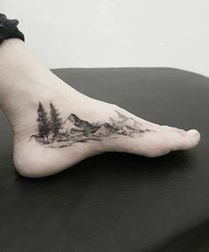 a person's foot with mountains and trees on it