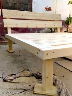 a wooden bench sitting on top of a cement floor next to a snake skin rug