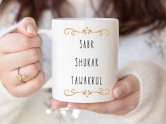 a woman holding a white coffee mug with the words saar shukar tahakki written on it