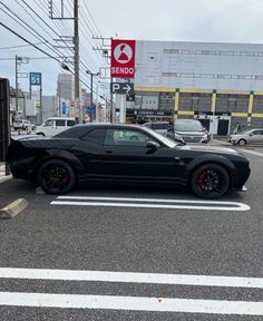 a black sports car parked on the side of the road in front of a gas station