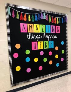 a bulletin board with the words amazing things happen here written in bright colors on it