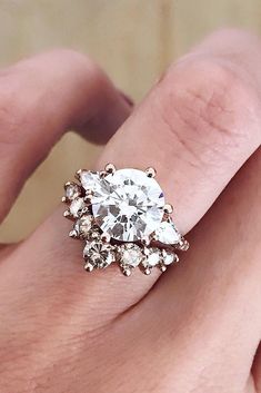 a woman's hand holding an engagement ring with three stones on the middle and one stone in the middle