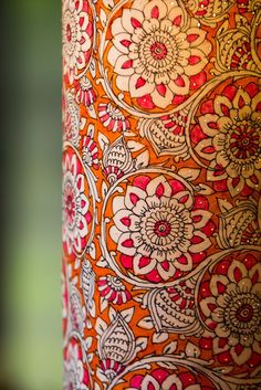 an orange and red vase with flowers on it