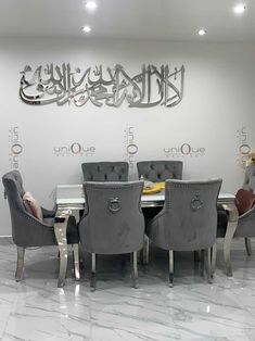 a dining room table and chairs with arabic calligraphy on the wall behind it in an office