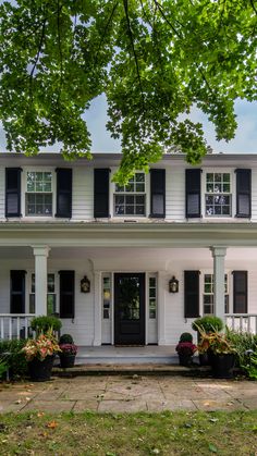 Grand House in Oakville in this picture. It has Beautiful White Wooden Siding, which gives it an Appearance that is Very Tidy and Clean. The Black Authentic Louvered Shutters offer a striking contrast, which contributes to the enhancement of the aesthetic appeal of the home. An Atmosphere of Timeless Elegance and Charm is Created as a Result of the Meticulously Kept Lawn, the Lush Greenery, and the Graceful Architecture all Working Together. White Siding Exterior Black Shutters, White Home Black Shutters, Black House White Shutters, Black Shutters White House, Houses With Black Shutters, White House With Black Shutters, Wooden Shutters Exterior, Black House Aesthetic, White Siding Exterior