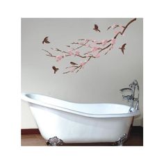 a white bath tub sitting next to a wall with pink flowers on the side and birds flying over it