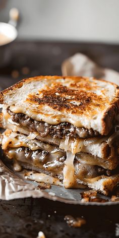 a grilled cheese and mushroom sandwich is on a metal plate with silverware next to it