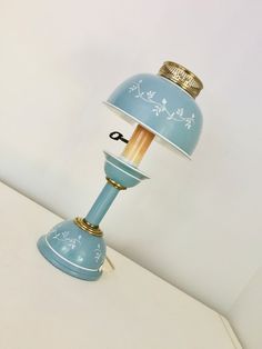 a table lamp with a blue shade and gold trimmings on the top, sitting on a white surface