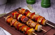 several skewers of meat and vegetables on a wooden board