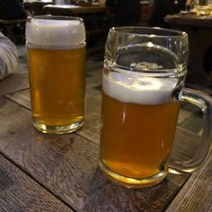 two mugs of beer sitting on top of a wooden table