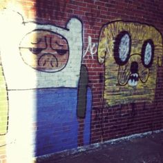 graffiti on the side of a brick building with two faces and one eye painted on it