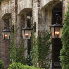 three lights are hanging from the side of a brick building with ivy growing on it