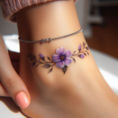 a close up of a person's foot with purple flowers on the ankle tattoo