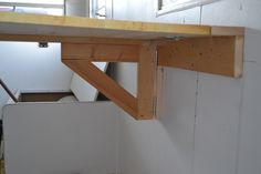 an unfinished wooden shelf in the corner of a room