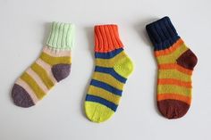 three pairs of colorful socks sitting next to each other on top of a white surface