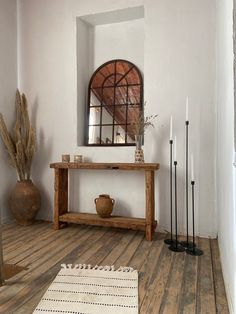 a wooden table sitting on top of a hard wood floor next to a tall mirror