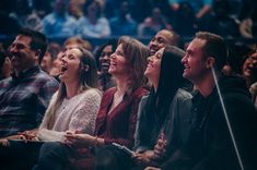 a group of people sitting next to each other in front of a crowd at a concert