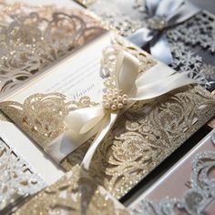 the wedding card is decorated with gold and silver paper, ribbon, and brooches