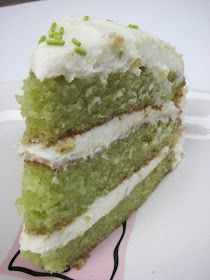 a piece of green cake with white frosting on a pink paper napkin sitting on top of a white plate