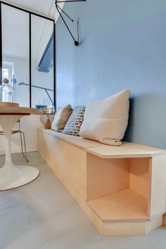 a room with blue walls and white flooring has a built in bench next to the window