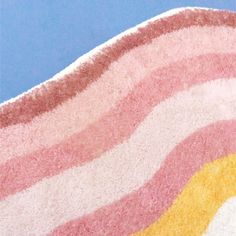 a pink, yellow and white striped rug on a blue surface with a small bird perched on it