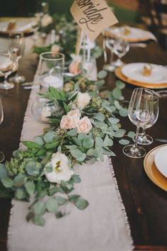 the table is set with white flowers and greenery