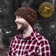 a man with a beard wearing a knitted hat in front of a tree trunk