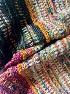 multicolored crocheted blanket laying on top of each other