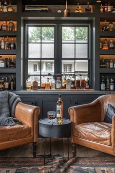 two leather chairs sitting next to each other in front of a bar with liquor bottles on the shelves