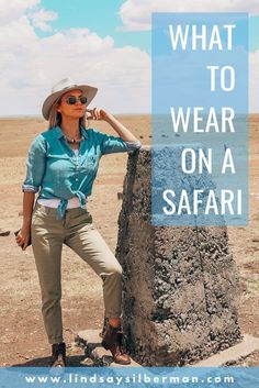 a woman leaning against a rock with the words what to wear on a safari