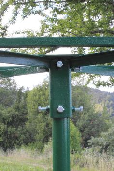 a green metal structure in the middle of a field