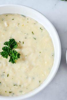 a white bowl filled with broccoli soup and garnished with parsley