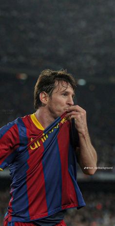 a man holding a soccer ball in his right hand and wearing a jersey with the word barcelona on it