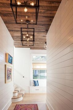 a hallway with white walls and wood ceilinging is lit by recessed light fixtures