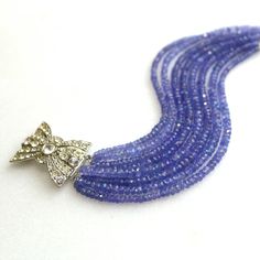 "A collection of very fine quality gemstones, these are sparkling tanzanite micro faceted gems with glittery shine and beautiful drape. The impressive nine strands are highlighted by a gorgeous vintage rhinestone box clasp to dress the inner or outer wrist and secures at 7.25\" long. When worn the strands all lay obediently side by side, not clustered as in the photos. The sparkle and flash that comes off of this tanzanite is glorious and utterly glamorous and this bracelet is sure to become a f Elegant Tanzanite Jewelry Hallmarked, Elegant Tanzanite Jewelry With Faceted Beads, Luxury Tanzanite Jubilee Bracelet, Anniversary Three-stone Tanzanite Jewelry, Classic Tanzanite Multi-stone Jewelry, Tanzanite Bracelet, Faceted Gems, Beautiful Drapes, Silver Rhinestone