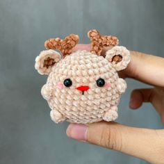 a hand holding a small stuffed animal in it's palm