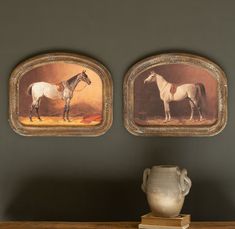 two framed horses are on the wall above a vase