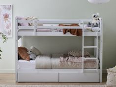 a white bunk bed sitting next to a wall with stuffed animals on top of it