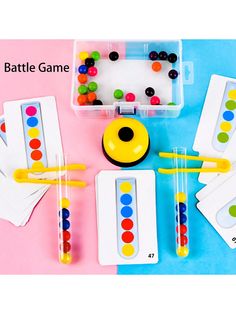 an assortment of different colored balls and sticks in a plastic container with matching game cards