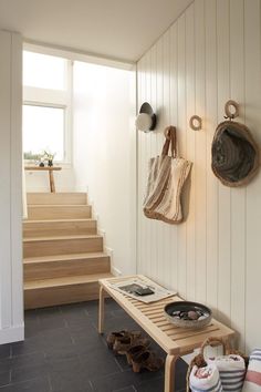 a wooden bench sitting under a window next to a set of stairs with shoes on it